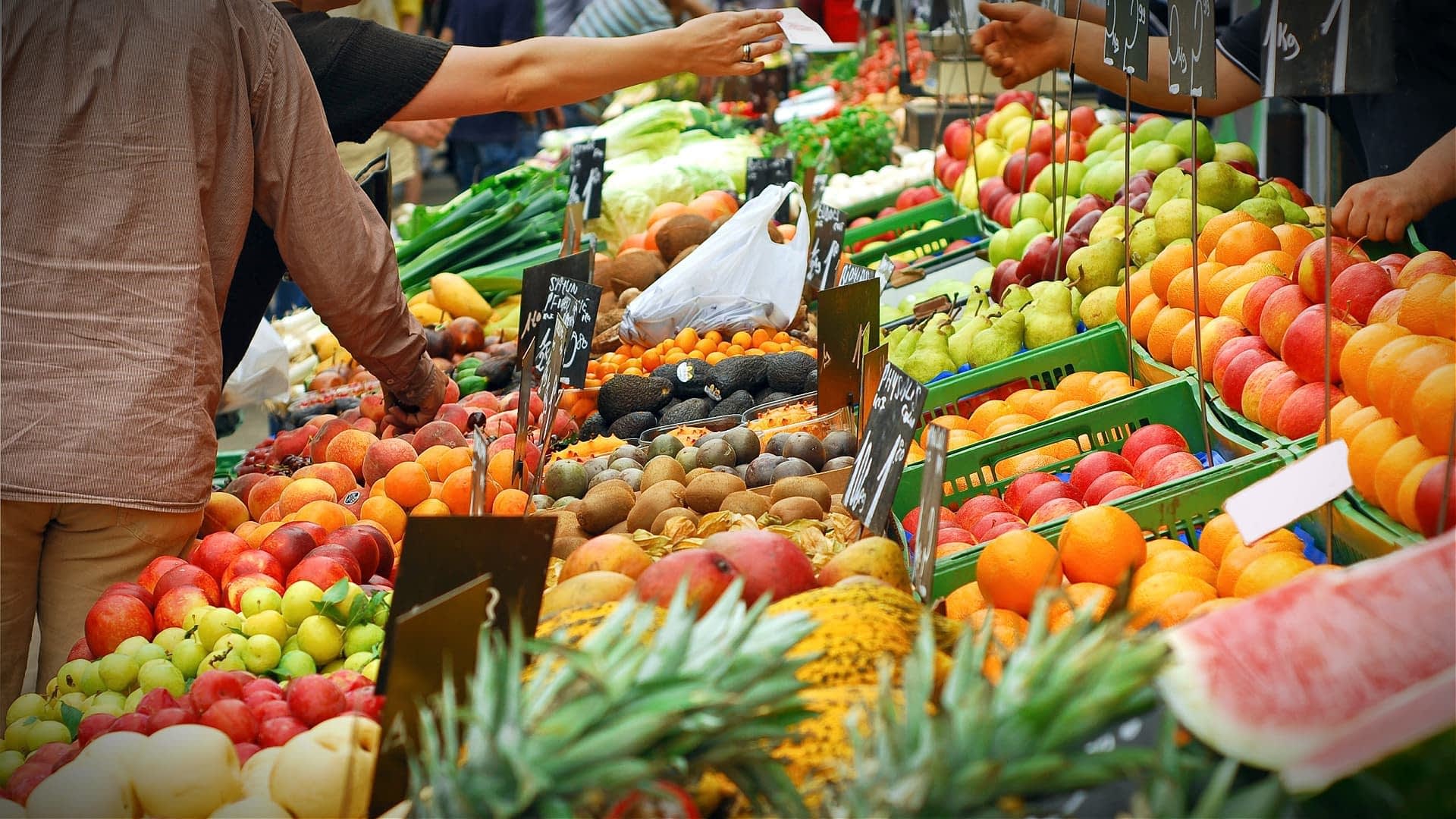 A market stall displaying a wide assortment of fresh fruits including apples, oranges, and avocados. - Olive Oil Times