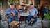 Two older men with hats sitting at a small round table in a café setting. - Olive Oil Times