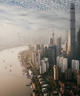 Aerial view of Shanghai skyline featuring tall buildings and a river flowing through the city. - Olive Oil Times