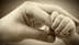 An adult hand gently holding a small baby hand in a close-up image. - Olive Oil Times
