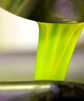 Bright green olive oil pouring from a metal container into a bowl. - Olive Oil Times
