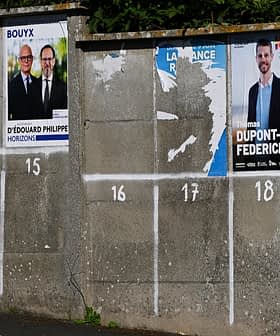 Various political campaign posters displayed on a concrete wall with numbered sections. - Olive Oil Times