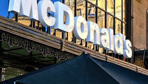 Signage of a McDonald's restaurant with reflective glass facade in the background. - Olive Oil Times