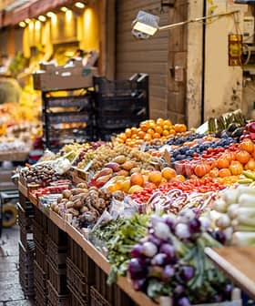 Vibrant display of various fruits and vegetables in a market setting with carts and crates. - Olive Oil Times