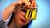 Person holding two small glass bottles containing olive oil with yellow liquid inside. - Olive Oil Times