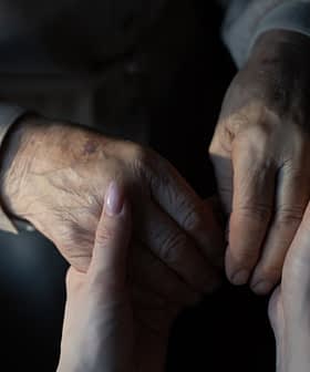 An elderly person's hand holding a younger person's hand, showcasing a connection between generations. - Olive Oil Times