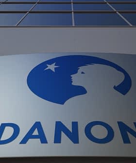 Danone company logo displayed on a building facade with a blue silhouette of a child's profile. - Olive Oil Times