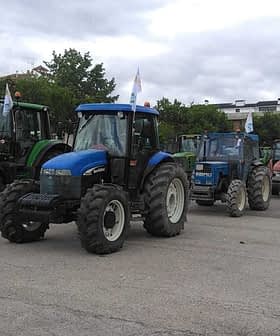 A row of agricultural tractors parked in a lot, featuring various colors and models. - Olive Oil Times