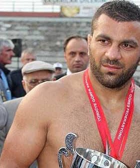 A shirtless wrestler holding a trophy while wearing a medal around his neck. - Olive Oil Times