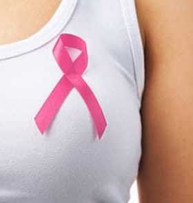 Close-up of a pink ribbon pinned on a white shirt worn by a person. - Olive Oil Times