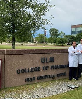 Group of five individuals in white lab coats standing in front of ULM College of Pharmacy sign. - Olive Oil Times