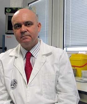 A man wearing a lab coat and a red tie sitting in a laboratory environment. - Olive Oil Times