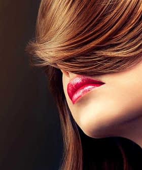 Profile view of a woman with long brown hair covering part of her face and red lips. - Olive Oil Times