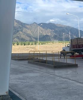 A truck parked in a loading area with mountains visible in the background. - Olive Oil Times