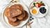 A plate of fried cinnamon French toast served with honey, berries, and a sprig of mint. - Olive Oil Times