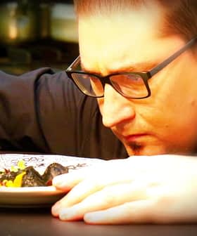 Chef closely inspecting a plate of food with a fork in hand, focused on the dish. - Olive Oil Times