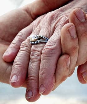 Close-up of two hands holding each other, one adorned with a silver ring. - Olive Oil Times