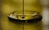 Stream of olive oil pouring into a circular pool of oil, creating ripples on the surface. - Olive Oil Times