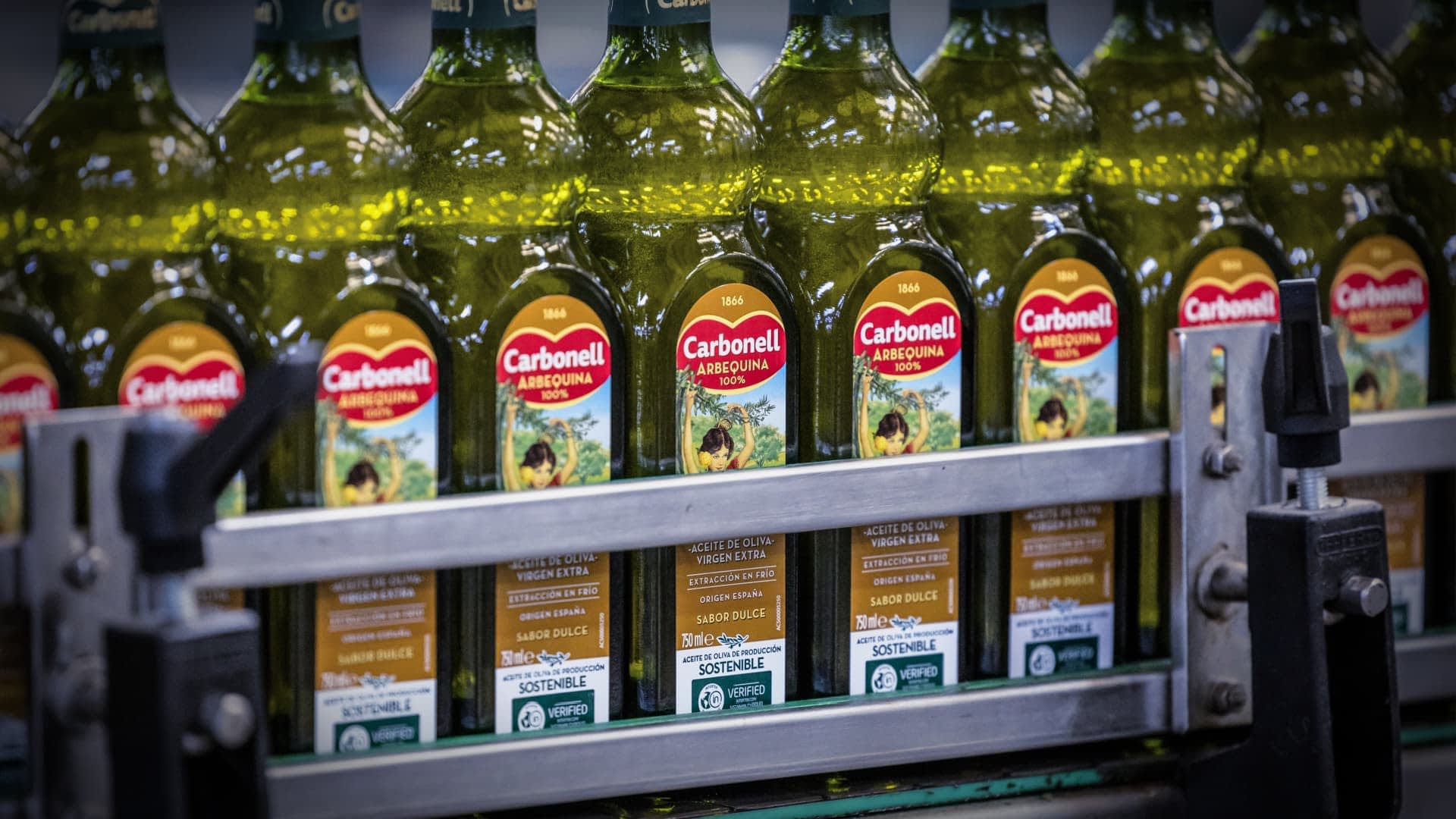 Rows of Carbonell olive oil bottles on a production line in a factory setting. - Olive Oil Times